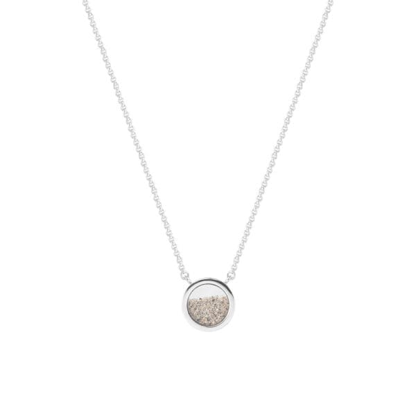 A round silver pendant with a free flowing mix of sand behind sapphire glass from front