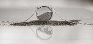 Silver pendant holding sand and its reflection showing a world map